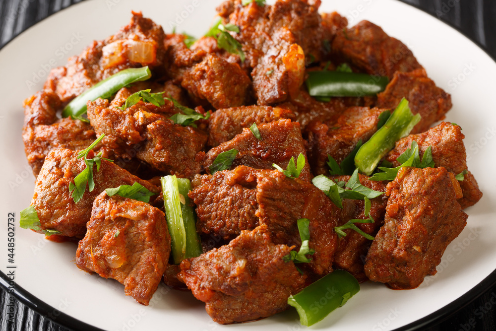 Tibs is an Ethiopian dish consisting of stir-fried meat and vegetables closeup in the plate on the table. Horizontal Tibs is an Ethiopian dish consisting of stir-fried meat and vegetables closeup in the plate on the table. Horizontal