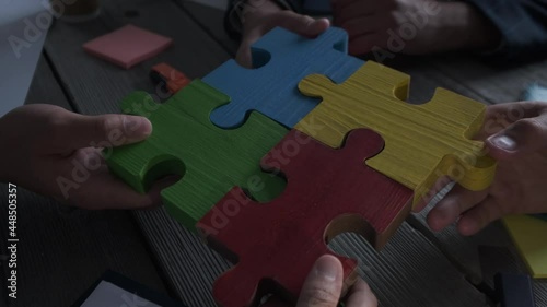 Hands group of business people assembling jigsaw puzzle white. Below is the graph diagram paper business documents placed on a wooden table in the meeting room.