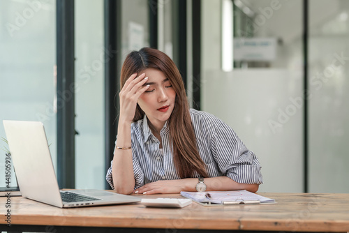 Asian businesswoman feeling tired headache stressed over document at the office.