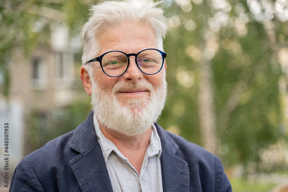 an elderly retired man with gray hair and a fashionable beard senior, businessman is happily sitting on the street an elderly retired man with gray hair and a fashionable beard senior, businessman is happily sitting on the street