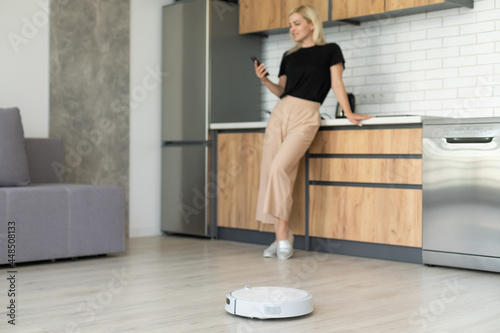 Modern life concept, woman relaxing , automatic robotic hoover clean the room while © Angelov