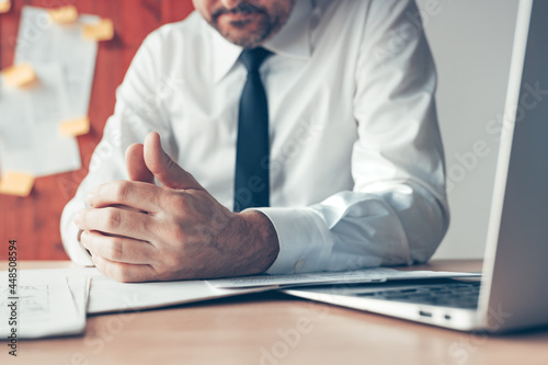 Bored businessman playing with thumbs of his hands in the office photo