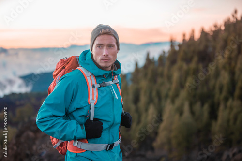 Man hiker hiking in mountain forest wearing cold weather accessories, wind jacket and backpack for camping outdoor. Guy portrait lifestyle.