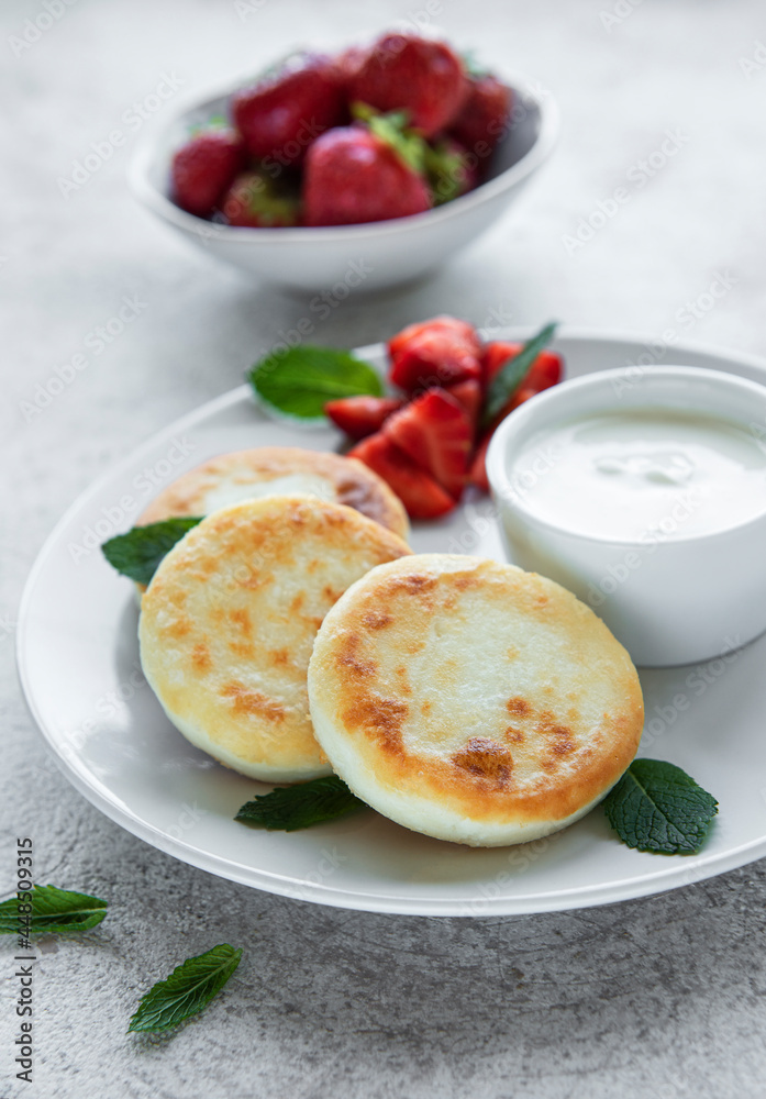 Cottage cheese pancakes, ricotta fritters on ceramic plate with  fresh strawberry.