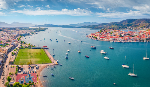 Fototapeta Naklejka Na Ścianę i Meble -  Collorful summer cityscape of Galatas town with public stadium. Splendid morning view of Poros port. Aerial morning seascape of Myrtoan Sea. Traveling concept background..