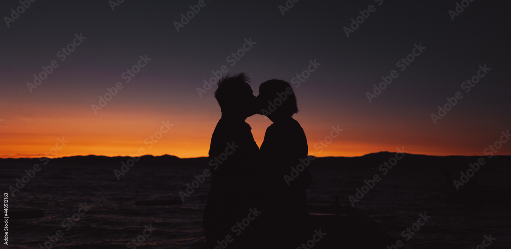 Couple of lovers kissing with sunset beach on the background - Focus on people silhouette