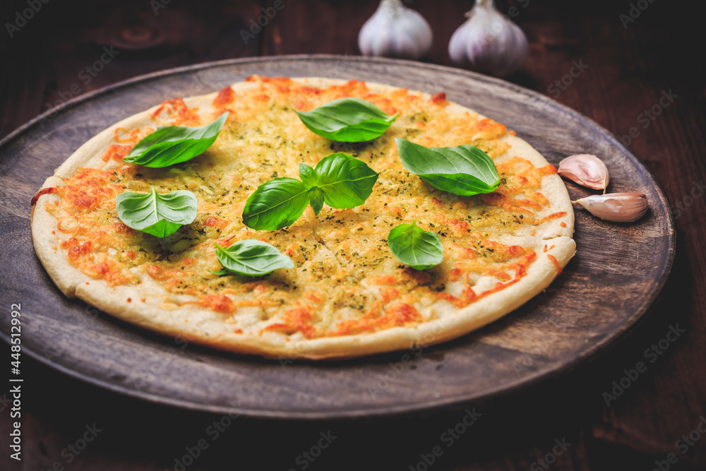 Pizza bread with garlic, cheese and basil on wooden background