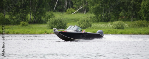 Obraz na płótnie Fast gliding Russian fishing motor boat side view on green trees on far shore background in Tver ragion at summer day, active recreation boating tourism on Volga river w salonie