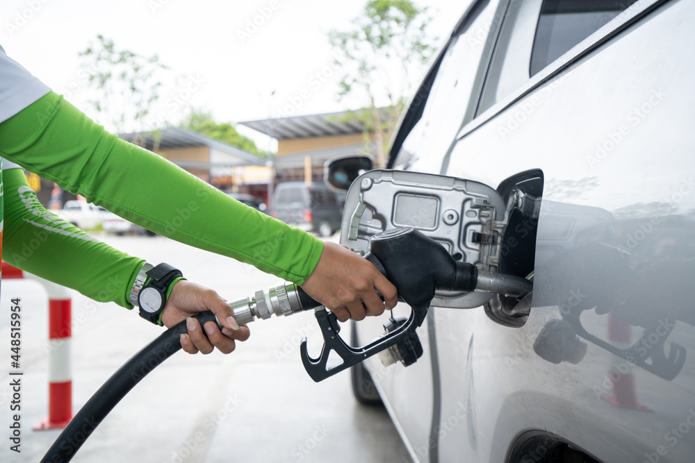 a woman pumping gasoline fuel in a car at gas station. a woman pumping gasoline fuel in a car at gas station.