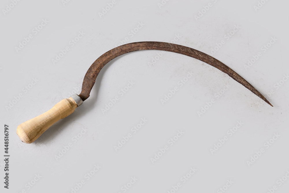 Old rusty serrated sickle on a light surface Old rusty serrated sickle on a light surface