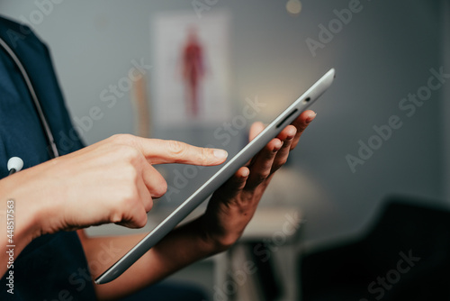 Caucasian female nurse typing on digital tablet in clinic