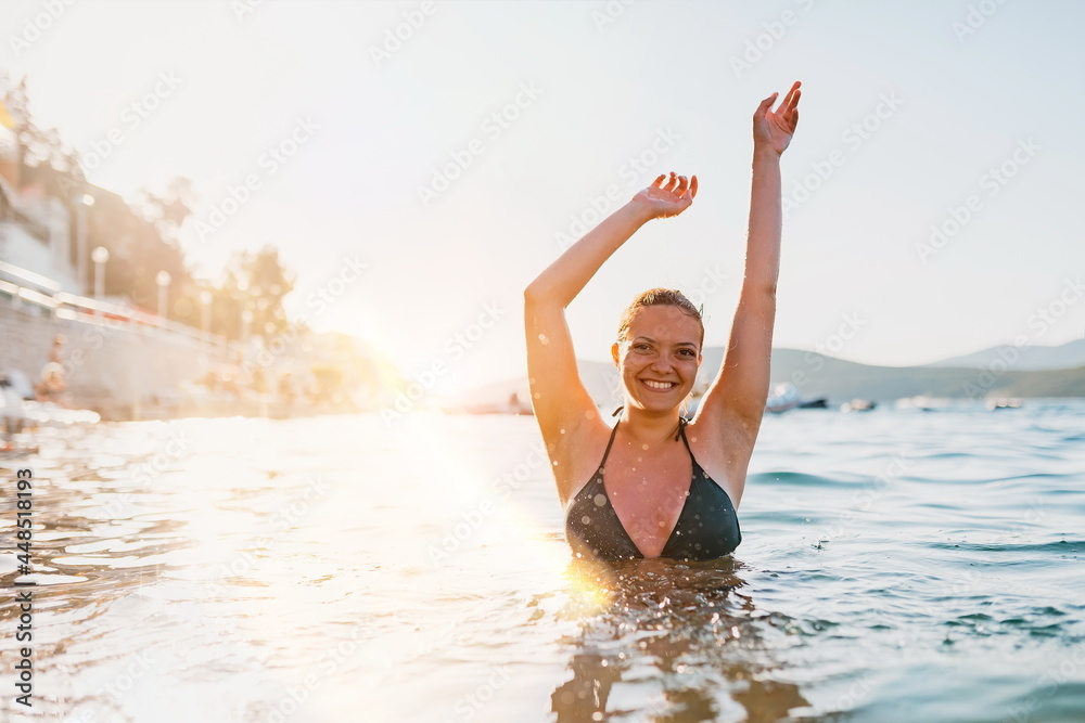 a beautiful woman in a swimsuit posing in the sea at sunset