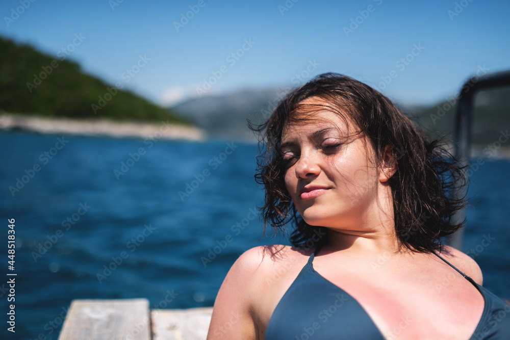 Beautiful woman in green bikini on tropical beach. Portrait of happy young woman smiling at sea. Brunette tanned girl in swimwear enjoying on beach.