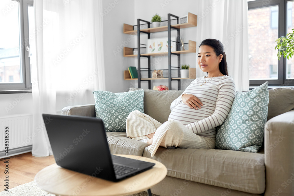 pregnancy, rest, people and expectation concept - pregnant asian woman with laptop computer sitting on sofa at home pregnancy, rest, people and expectation concept - pregnant asian woman with laptop computer sitting on sofa at home