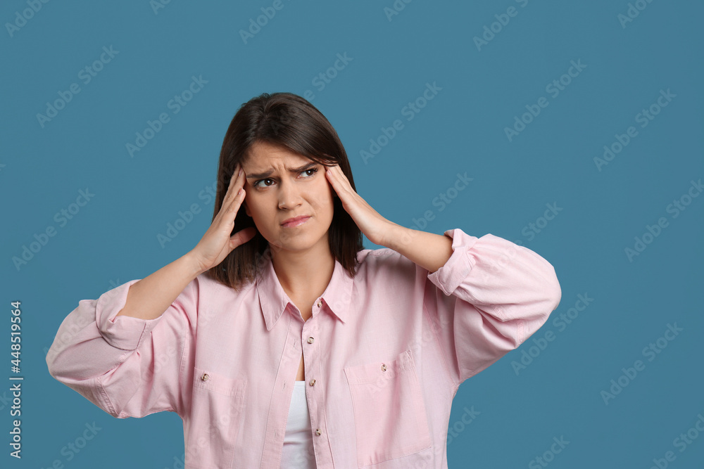 Young woman suffering from migraine on light blue background Young woman suffering from migraine on light blue background