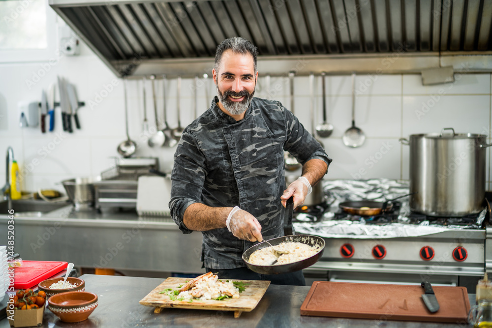 Professional cook is serving meal in restaurant's kitchen. Professional cook is serving meal in restaurant's kitchen.