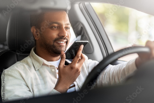 transport, people and technology concept - smiling indian man or driver driving car and recording message using voice command recorder on smartphone © Syda Productions