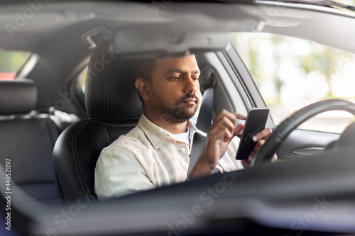 transport, people and technology concept - indian man or driver using smartphone in car