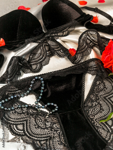 Set of women's black lace underwear bra and panties on a silk sheet subject photo close-up.