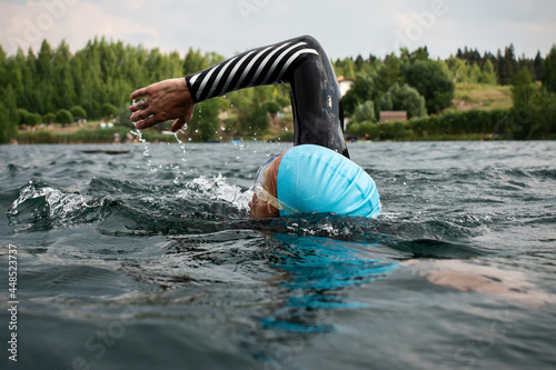 Athletic young man swimming at lake. Professional triathlon swimmer in action. Young man athlete practicing at open water