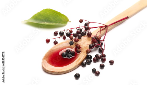 Fotografija Squeezed elderberries juice, syrup in wooden spoon with elder berries and leaves