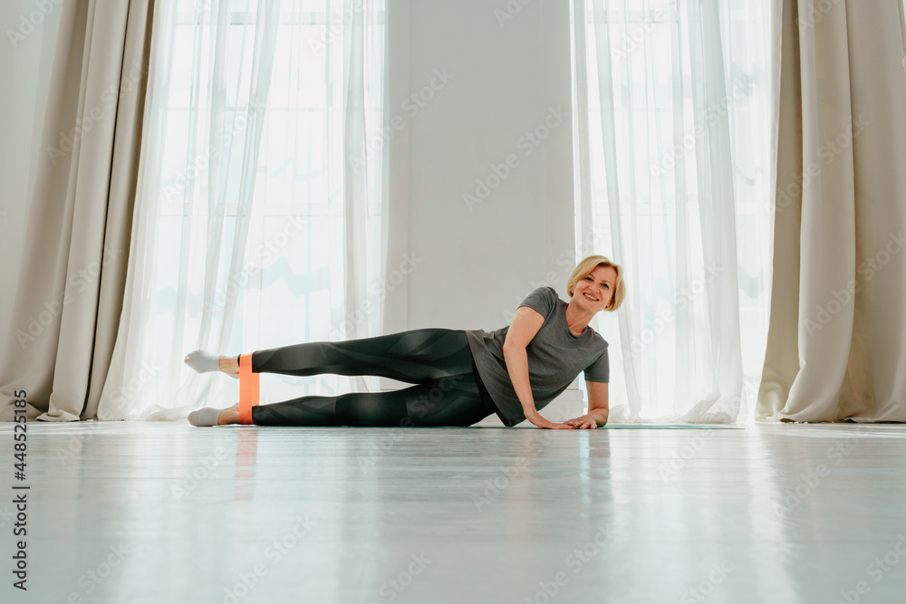 Sportive woman does warming exercise at home with elastic