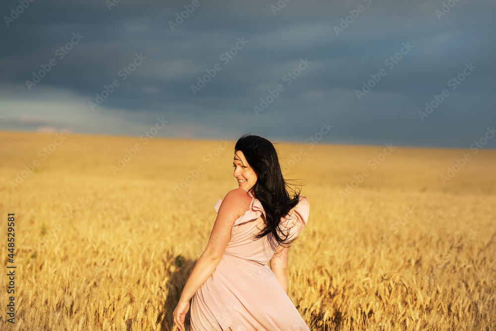 A girl in a dress with long hair in a wheat field in the evening dramatic light. A girl in a dress with long hair in a wheat field in the evening dramatic light.