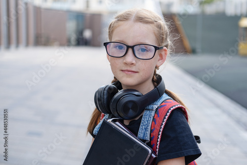 Portrait of sming redhead Caucasian girl with ponytail and backpack outdoor photo