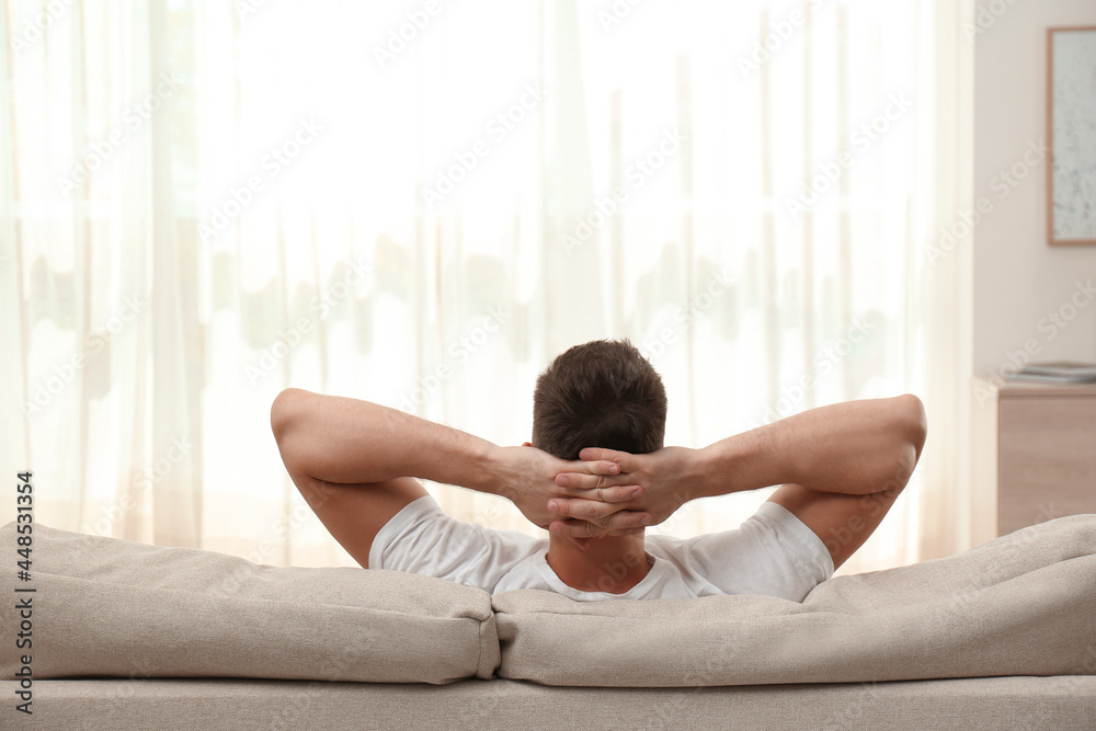 Man relaxing on sofa at home, back view Man relaxing on sofa at home, back view
