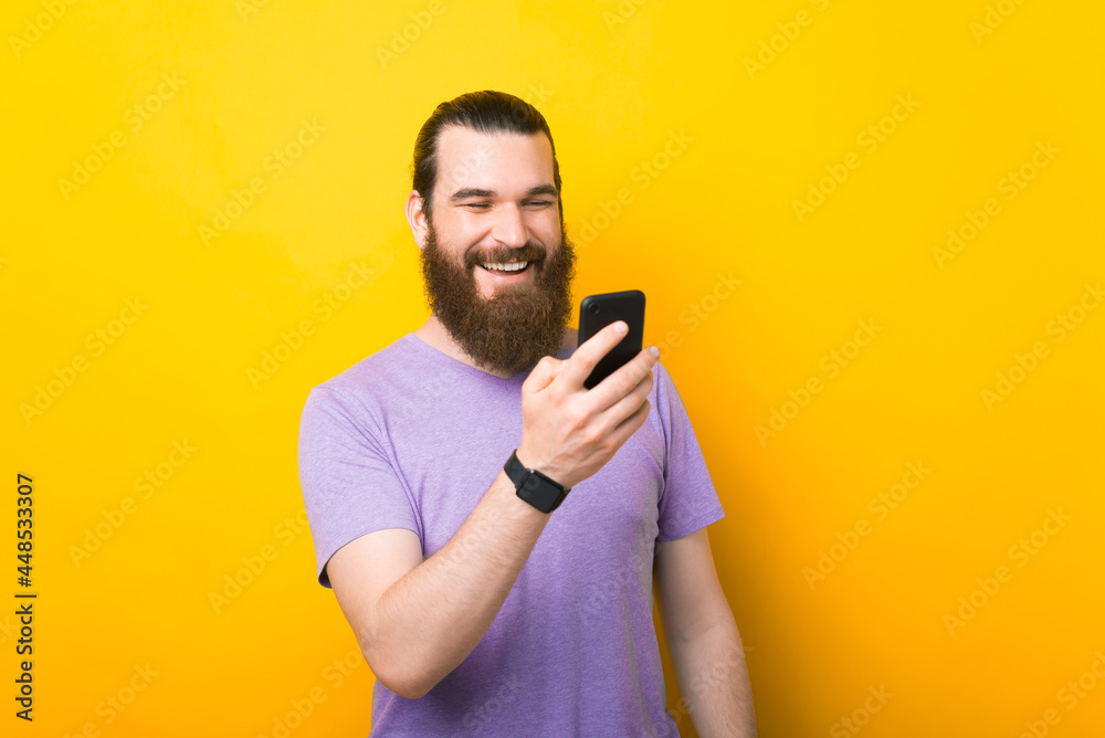 A joyful bearded man is chatting happily with someone on his new smartphone A joyful bearded man is chatting happily with someone on his new smartphone