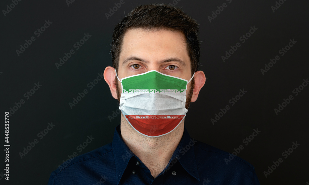 Man wearing Iranian flag protective medical face mask. He looks worried and concerned. Coronavirus concept in Iran with black background. Man wearing Iranian flag protective medical face mask. He looks worried and concerned. Coronavirus concept in Iran with black background.