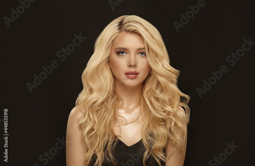 blonde woman with long curly hair, beauty shot in black background.