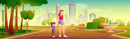 Mother and little daughter walk in city park.