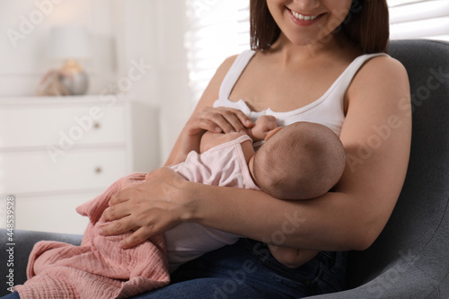 Young woman breastfeeding her little baby at home, closeup