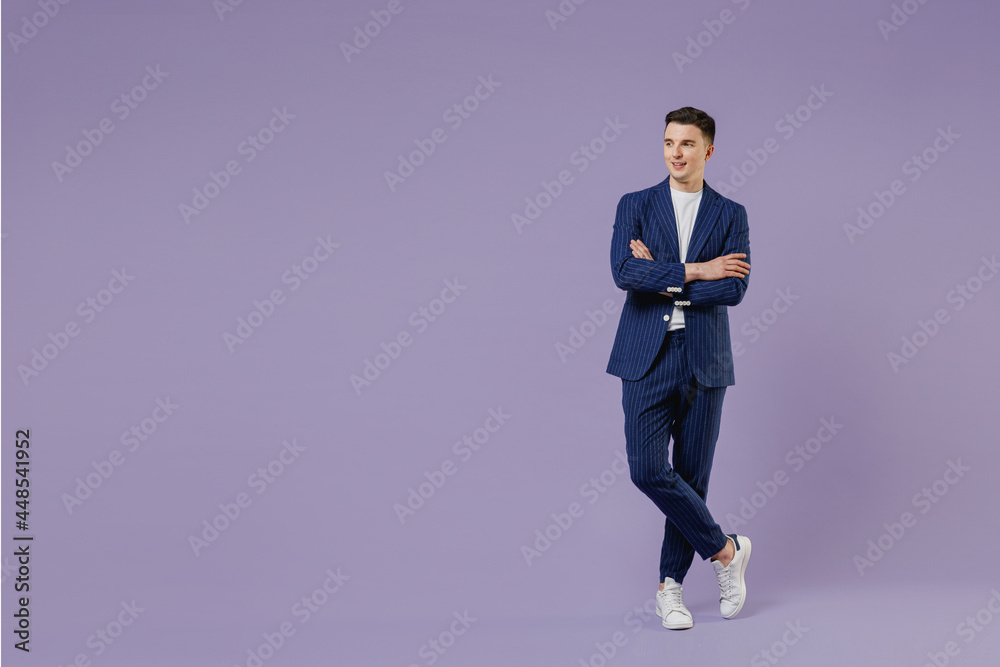 Full size happy young successful employee business man lawyer 20s wear formal blue suit white t-shirt work in office hold hands crossed look aside isolated on pastel purple background studio portrait. Full size happy young successful employee business man lawyer 20s wear formal blue suit white t-shirt work in office hold hands crossed look aside isolated on pastel purple background studio portrait.