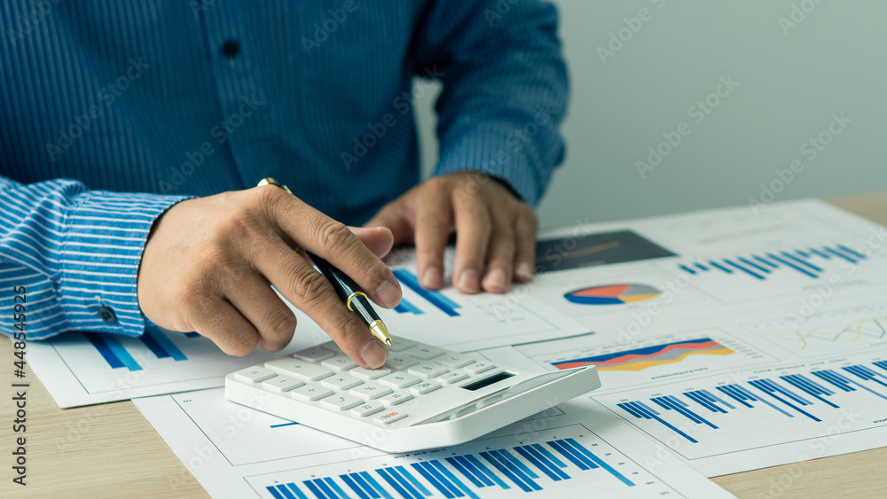 Accountant using computer with clamp and graph document, business man working on desk using calculator to calculate numbers, financial accounting concepts. Accountant using computer with clamp and graph document, business man working on desk using calculator to calculate numbers, financial accounting concepts.