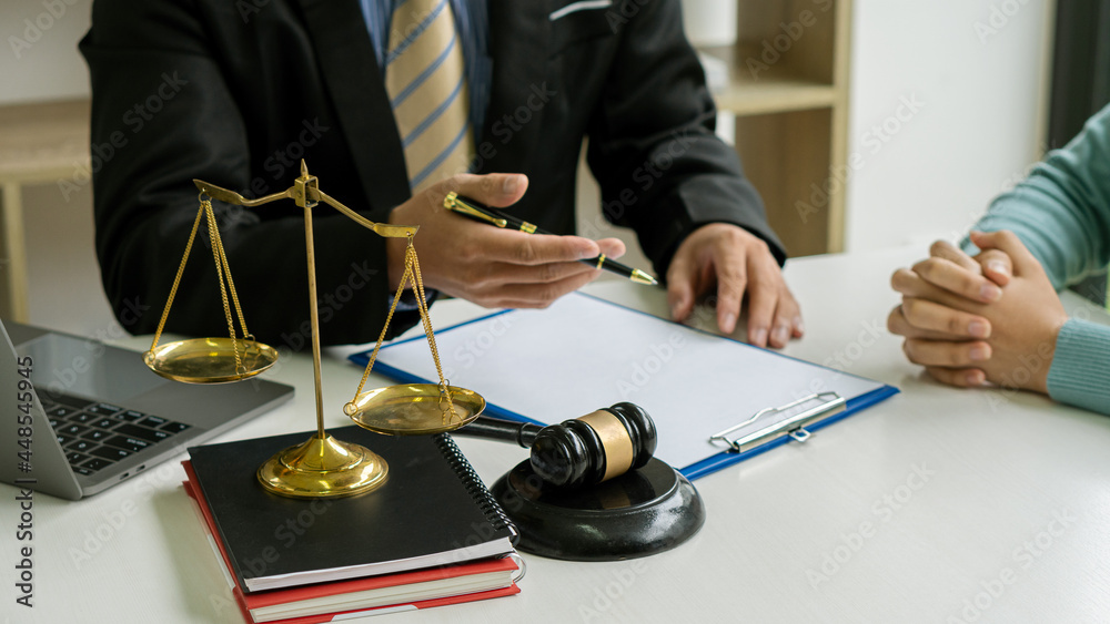 Consulting of businessmen and male lawyers or judges with team meetings with clients. Legal services concept with hammer and scales with contract documents with laptop on table.