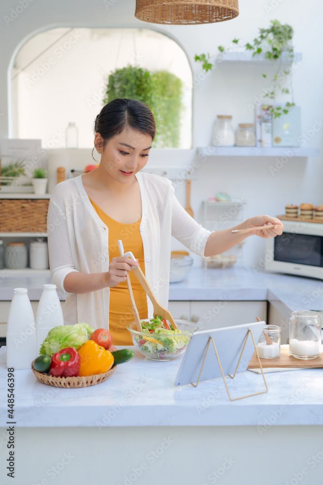 Beautiful young woman with tablet computer cooking in kitchen Beautiful young woman with tablet computer cooking in kitchen