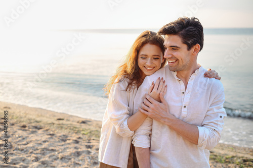 Print op canvas Smiling young couple two friends family man woman 20s in casual clothes hug girlfriend put head on boyfriend shoulder at sunrise over sea sand beach ocean outdoor seaside in summer day sunset evening