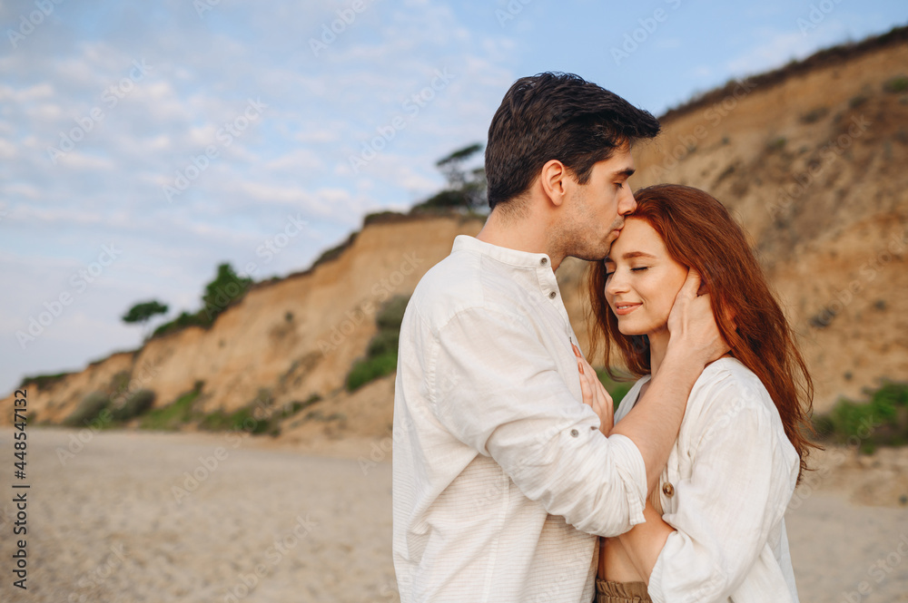 Side view close up smiling happy young tender couple two friends family man woman in casual clothes hug each other kiss forehead at sunrise over sea beach outdoor seaside in summer day sunset evening Side view close up smiling happy young tender couple two friends family man woman in casual clothes hug each other kiss forehead at sunrise over sea beach outdoor seaside in summer day sunset evening