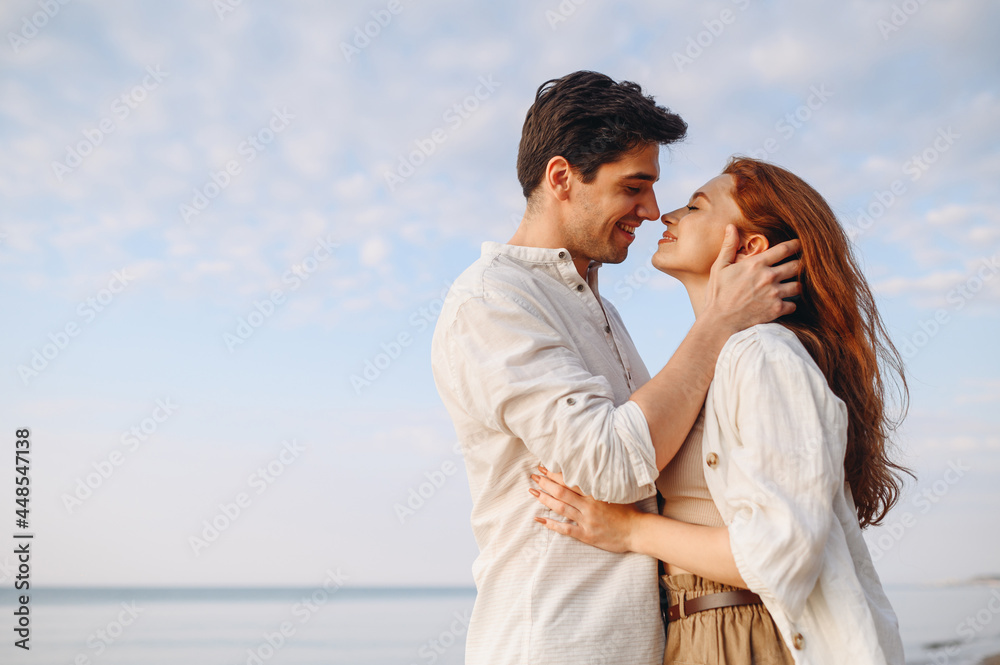 Side view happy young couple two friends family man woman 20s wearing casual clothes hug each other going to kiss at sunrise over sea beach ocean outdoor exotic seaside in summer day sunset evening.