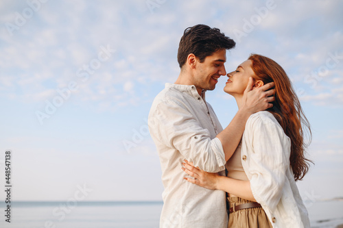 Side view happy young couple two friends family man woman 20s wearing casual clothes hug each other going to kiss at sunrise over sea beach ocean outdoor exotic seaside in summer day sunset evening.