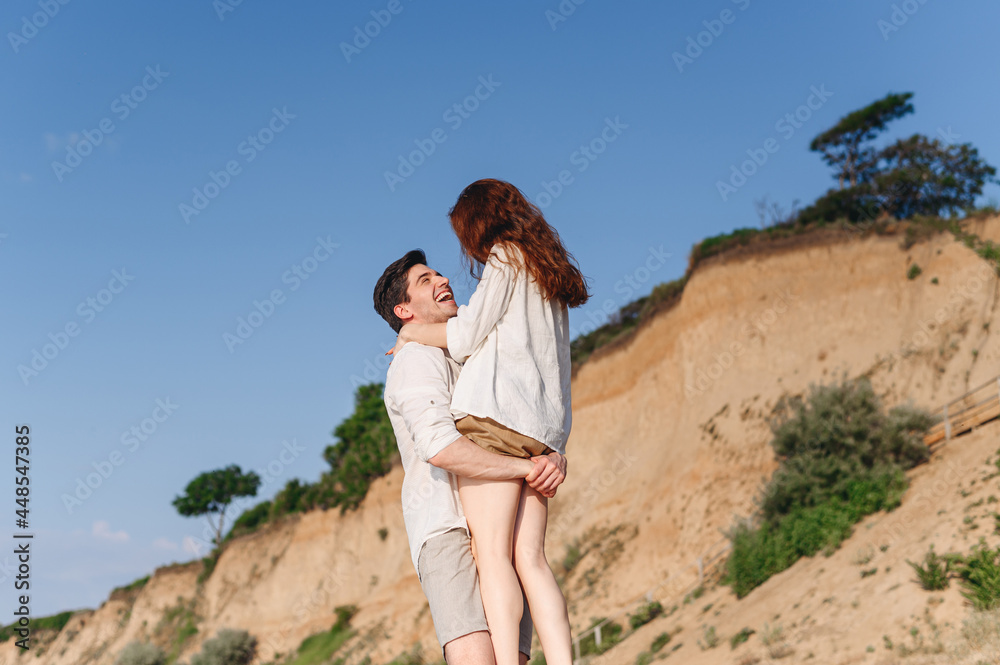 Side view happy fun young couple two friends family man woman in white clothes boyfriend hug hold girlfriend at sunrise over sea sand beach ocean outdoor exotic seaside in summer day sunset evening.