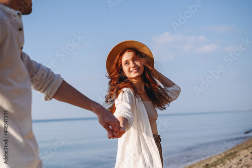 Fotografía Charming happy young couple two family man woman in white clothes hold hands follow me look to each other walk together at sunrise over sea beach ocean outdoor exotic seaside in summer day evening