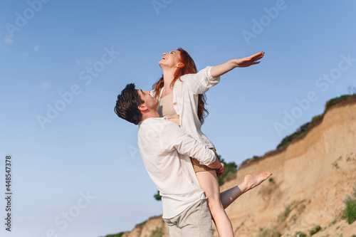 Side view excited young couple two friend family man woman in white clothes boyfriend hold girlfriend with outsretched arms at sunrise over sea sand beach outdoor seaside in summer day sunset evening