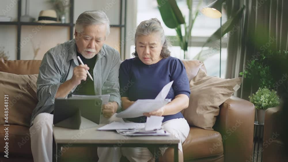 old retired asian senior couple checking and calculate financial billing together on sofa involved in financial paperwork, paying taxes online using e-banking laptop at living room home background old retired asian senior couple checking and calculate financial billing together on sofa involved in financial paperwork, paying taxes online using e-banking laptop at living room home background