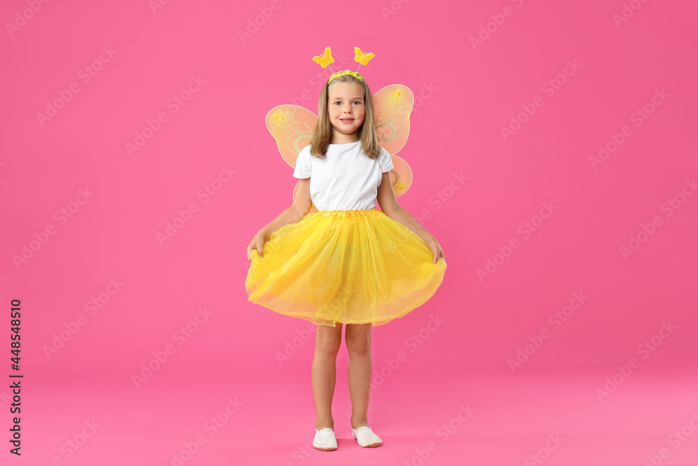 Cute little girl in fairy costume with yellow wings on pink background
