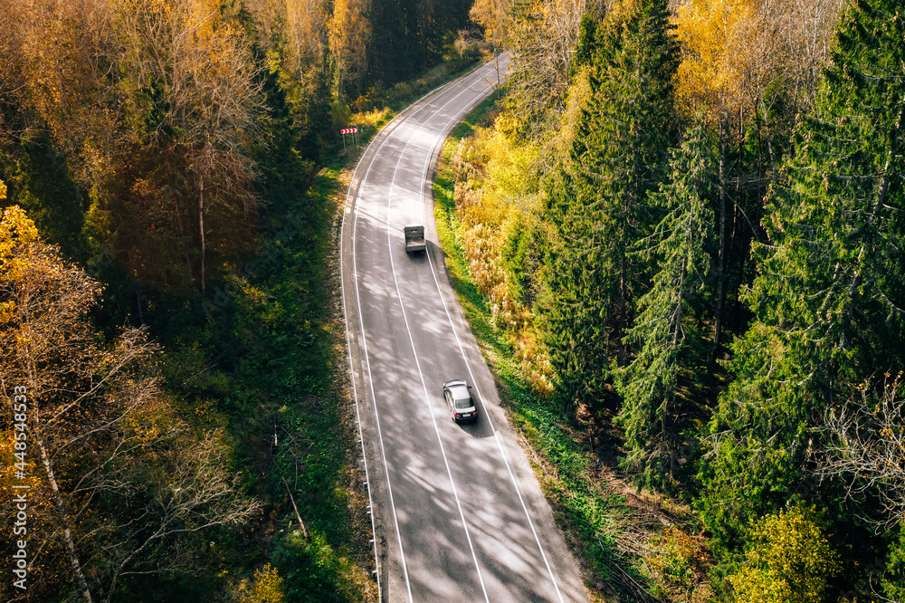 Fototapeta premium Aerial view of fall road and car through the autumn forest