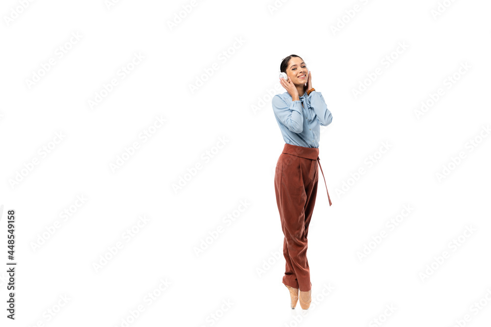 Smiling ballerina in headphones looking at camera isolated on white