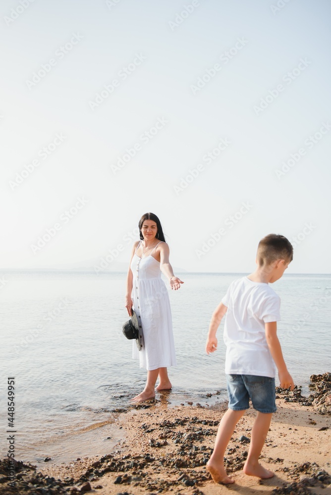 Happy mother and son walk along the ocean beach having great family time on vacation on Pandawa Beach, Bali. Paradise, travel, vacation concept